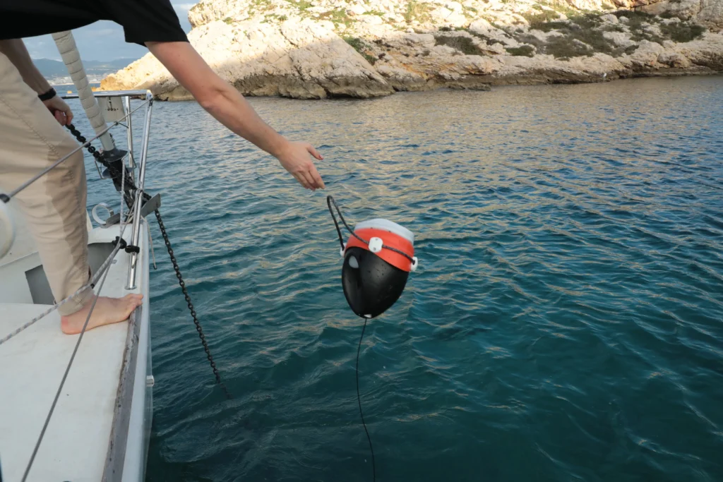 A sailor sets ready to deploy the anchor |alarm buoy to detect anchor dragging